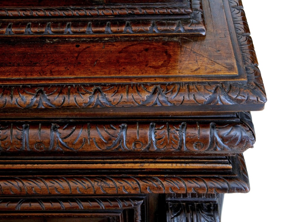 A two-section mid-19th century dark walnut cabinet featuring detailed relief carvings on the panelled doors, fluted columns, and flattened bun feet. View VII
