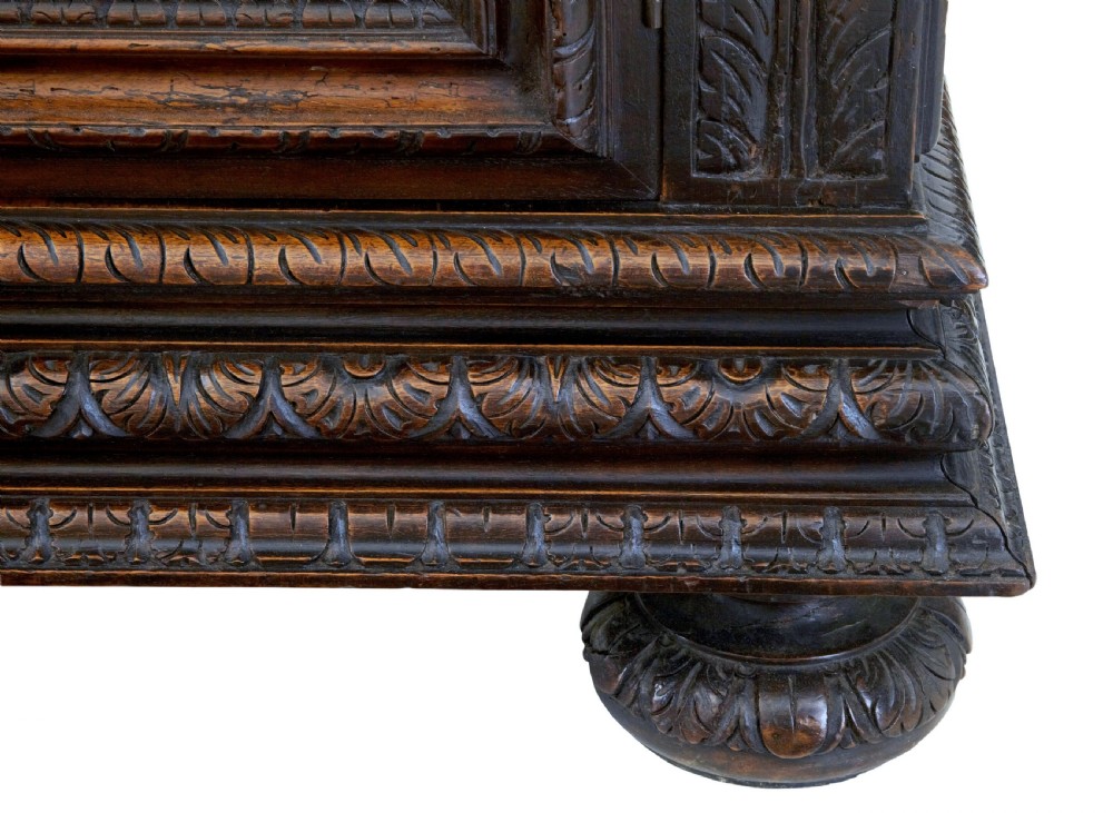 A two-section mid-19th century dark walnut cabinet featuring detailed relief carvings on the panelled doors, fluted columns, and flattened bun feet. View VIII