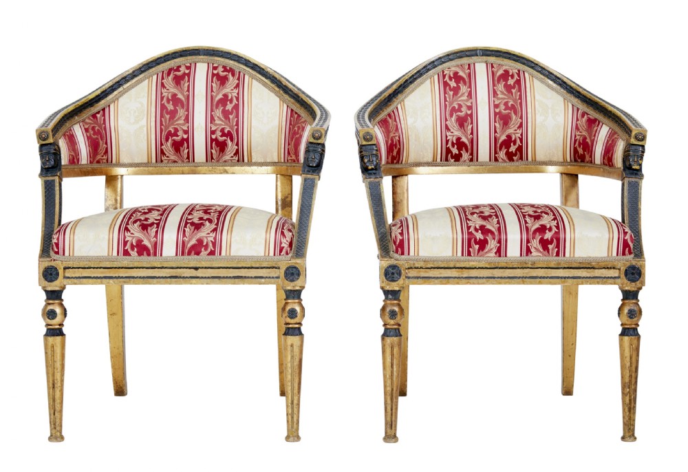 A pair of 19th-century Swedish giltwood armchairs featuring curved backs, black carved terminals with female heads, and red and cream striped fabric upholstery.