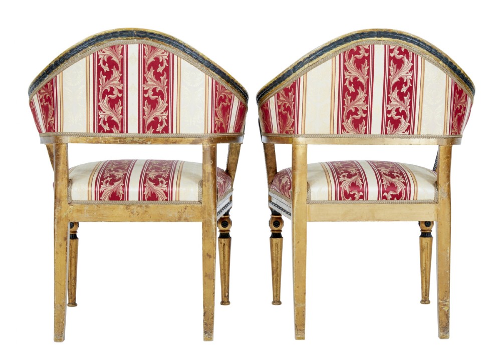 A pair of 19th-century Swedish giltwood armchairs featuring curved backs, black carved terminals with female heads, and red and cream striped fabric upholstery. View III