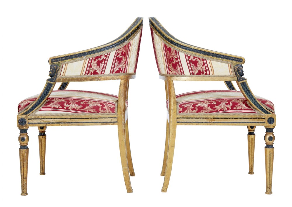 A pair of 19th-century Swedish giltwood armchairs featuring curved backs, black carved terminals with female heads, and red and cream striped fabric upholstery. View IV