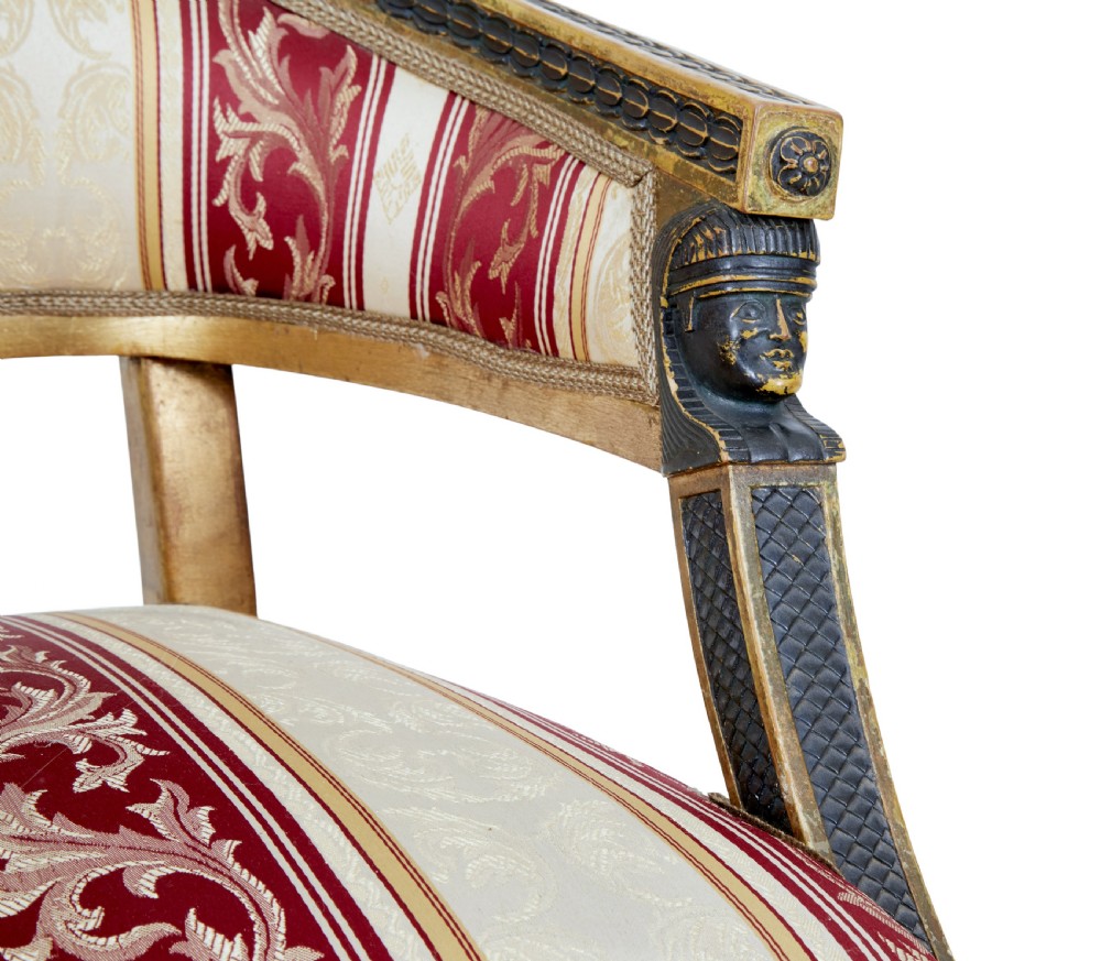 A pair of 19th-century Swedish giltwood armchairs featuring curved backs, black carved terminals with female heads, and red and cream striped fabric upholstery. View VI