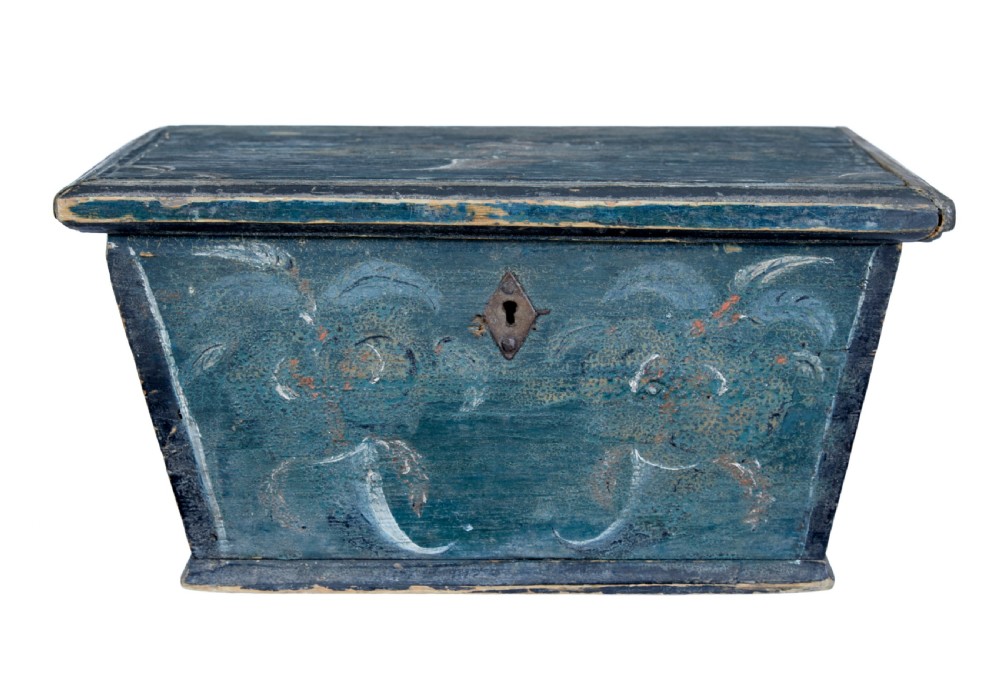 A small 19th-century wooden sarcophagus box featuring distressed blue paint, white hand-painted decorative flourishes, and a central diamond-shaped iron keyhole escutcheon.