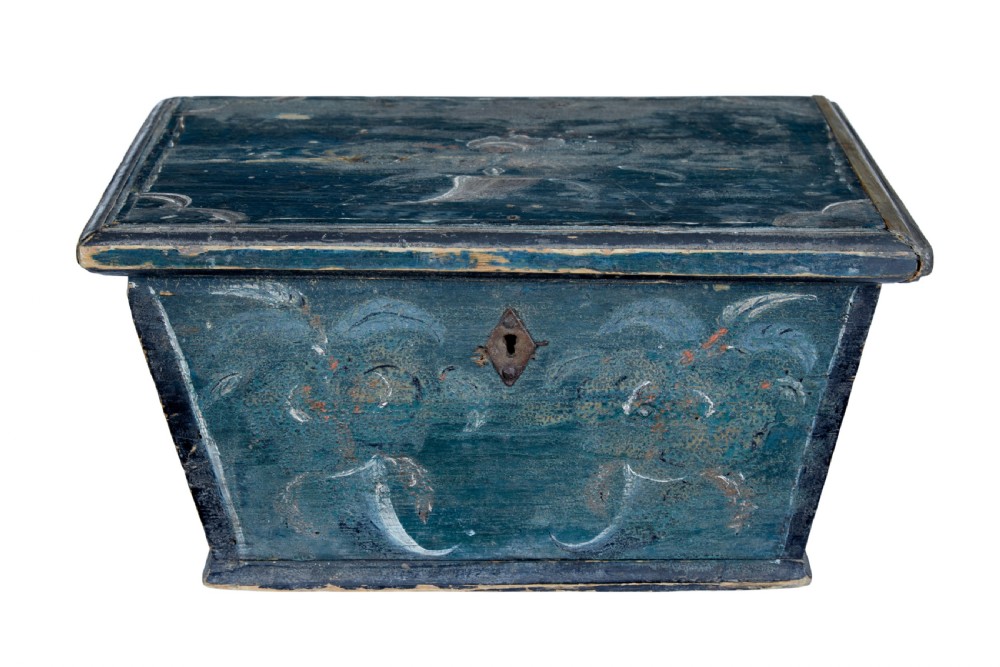 A small 19th-century wooden sarcophagus box featuring distressed blue paint, white hand-painted decorative flourishes, and a central diamond-shaped iron keyhole escutcheon. View II