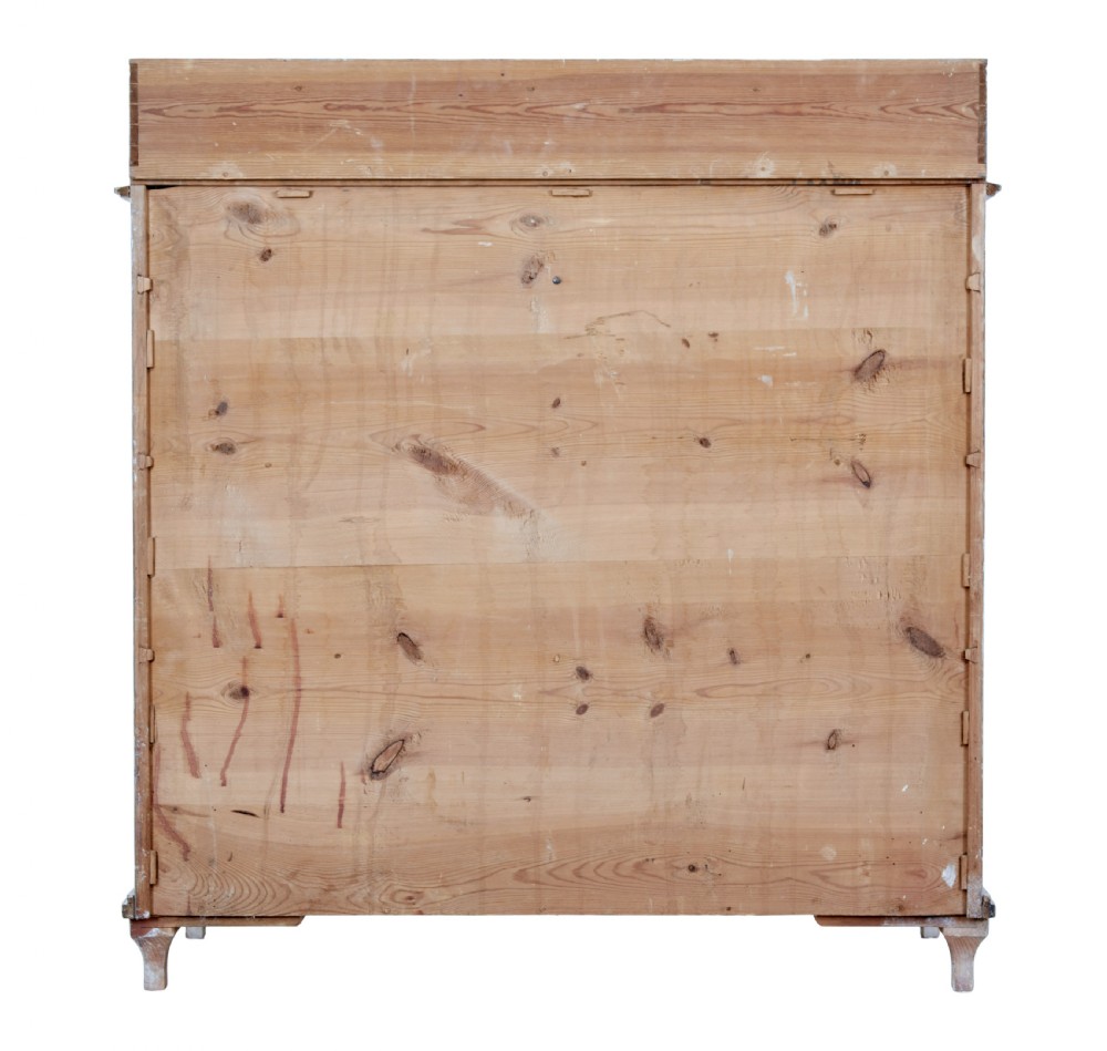 A 19th-century Swedish pine cupboard featuring distressed off-white painted finishes, double doors carved with diamond motifs, tapered short legs, and a low gallery top. View V