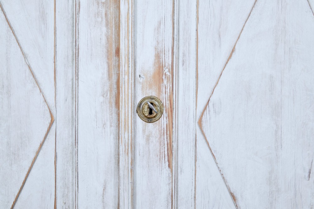 A 19th-century Swedish pine cupboard featuring distressed off-white painted finishes, double doors carved with diamond motifs, tapered short legs, and a low gallery top. View VII
