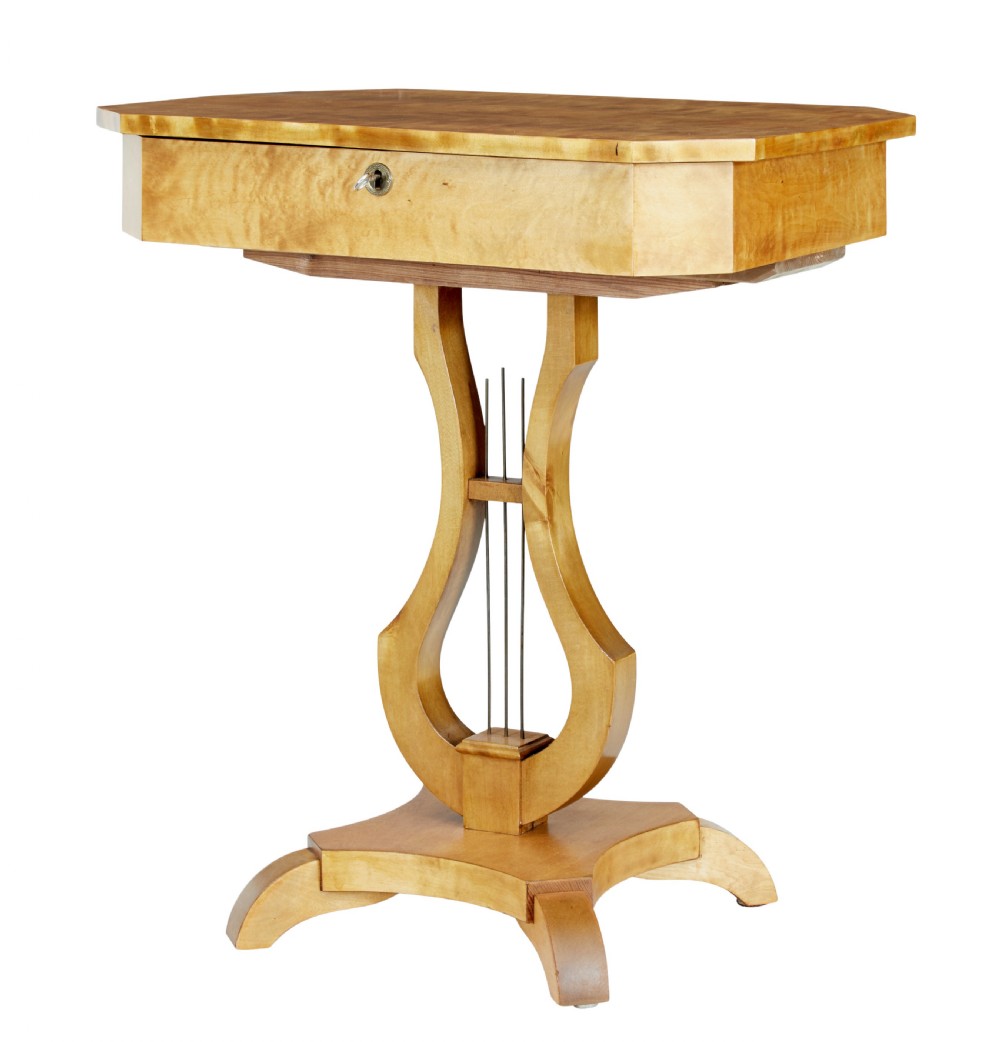 A 19th-century Swedish satin birch occasional table featuring a lyre-shaped pedestal base, a single drawer with a key, and a quadruped plinth.