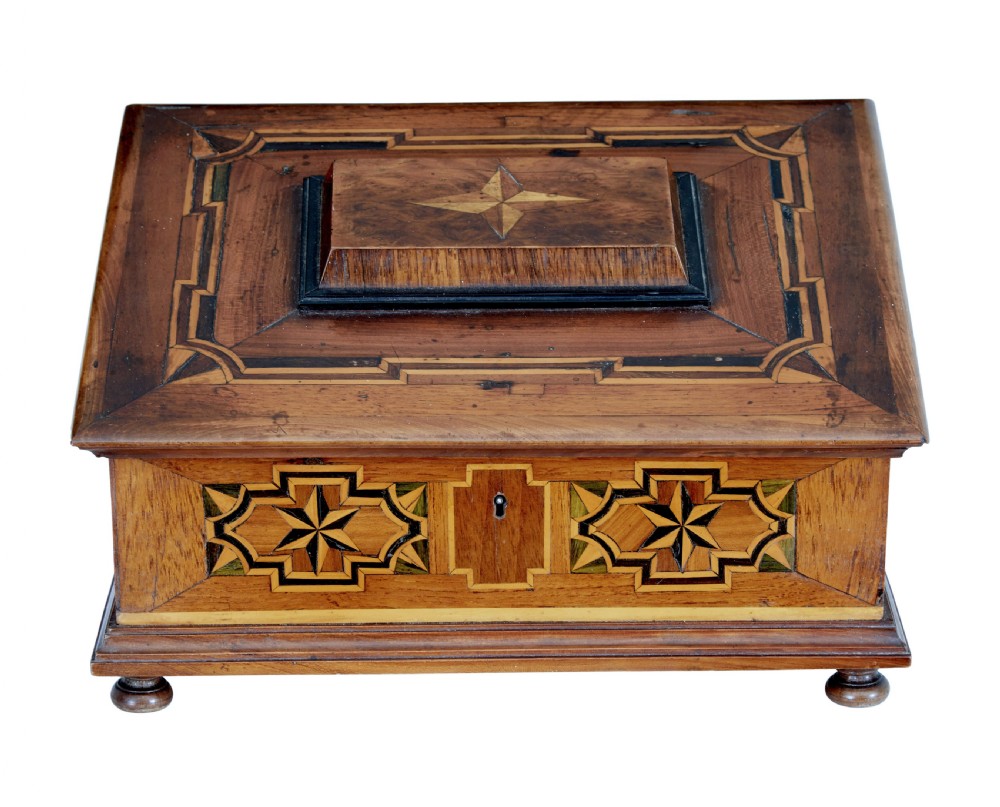A 19th-century fruitwood desktop box featuring geometric marquetry star motifs, a raised stepped lid, keyhole, and small turned feet.