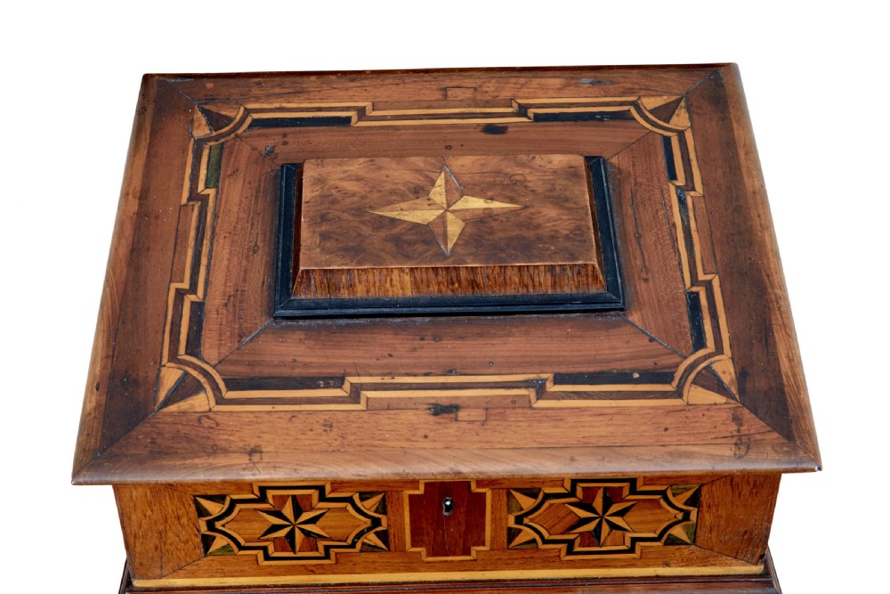 A 19th-century fruitwood desktop box featuring geometric marquetry star motifs, a raised stepped lid, keyhole, and small turned feet. View V
