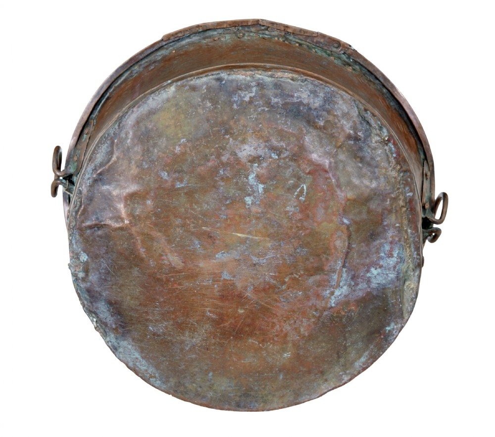 A large 19th-century copper pot with embossed spiral patterns, riveted side seams, a wide flared rim, and two round metal ring handles. View V