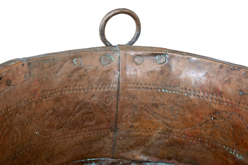 A large 19th-century copper pot with embossed spiral patterns, riveted side seams, a wide flared rim, and two round metal ring handles. View VI