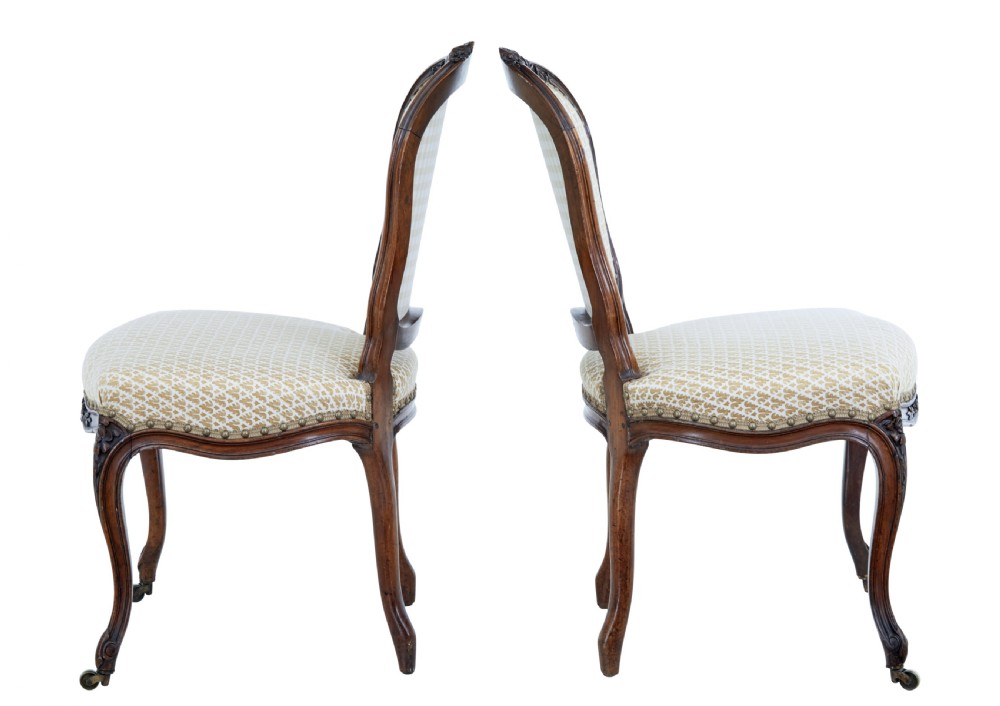 A pair of 19th-century carved walnut side chairs with patterned beige upholstery, cabriole legs, and brass castors. View II