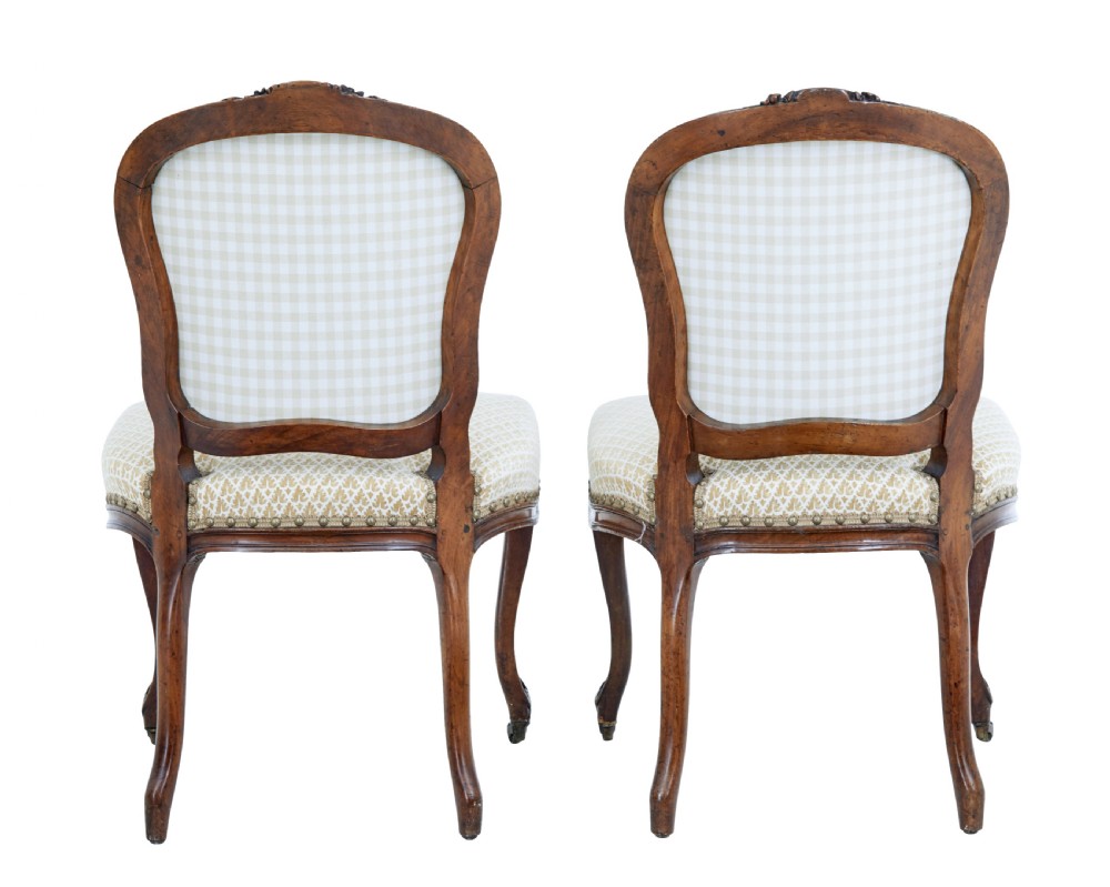 A pair of 19th-century carved walnut side chairs with patterned beige upholstery, cabriole legs, and brass castors. View III