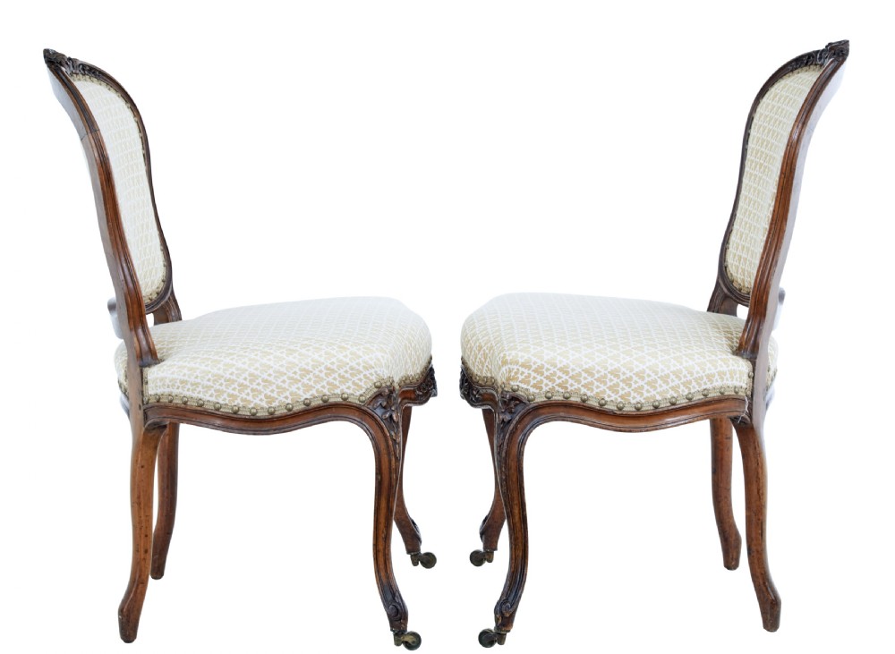 A pair of 19th-century carved walnut side chairs with patterned beige upholstery, cabriole legs, and brass castors. View IV