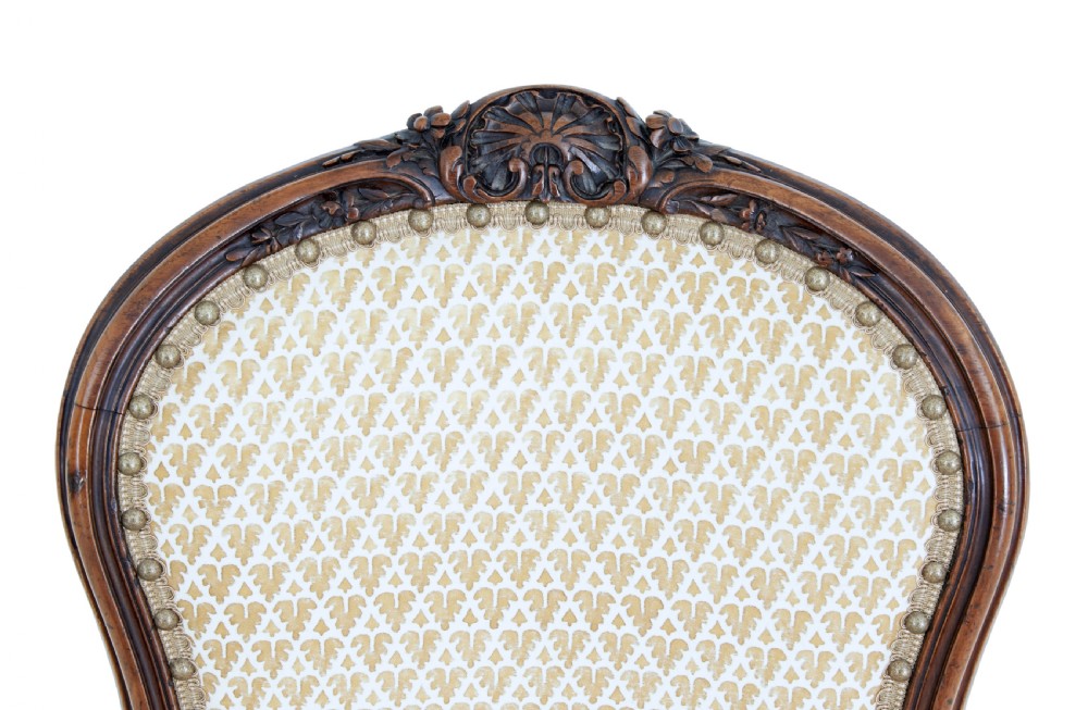 A pair of 19th-century carved walnut side chairs with patterned beige upholstery, cabriole legs, and brass castors. View VI