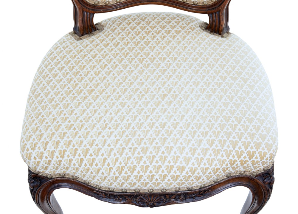 A pair of 19th-century carved walnut side chairs with patterned beige upholstery, cabriole legs, and brass castors. View VII