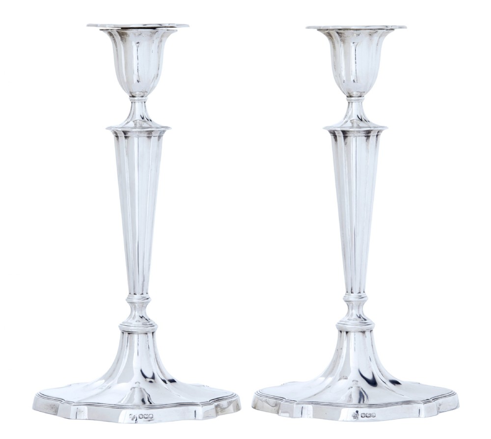 A pair of polished early twentieth century sterling silver candlesticks featuring fluted tapering stems and shaped stepped bases with hallmark stamps.