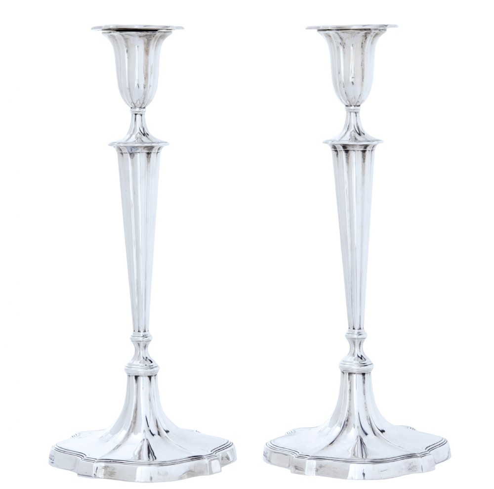 A pair of polished early twentieth century sterling silver candlesticks featuring fluted tapering stems and shaped stepped bases with hallmark stamps. View II