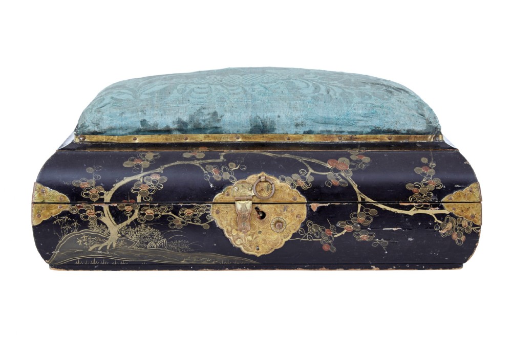 A 19th-century black lacquered jewellery box decorated with gilded botanical motifs, an ornate brass clasp, and a pale blue padded silk top.