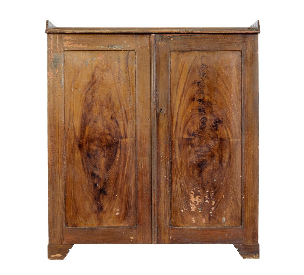 A 19th-century Swedish pine cupboard featuring two panelled doors with faux-wood grain paintwork and a low shaped splashback.