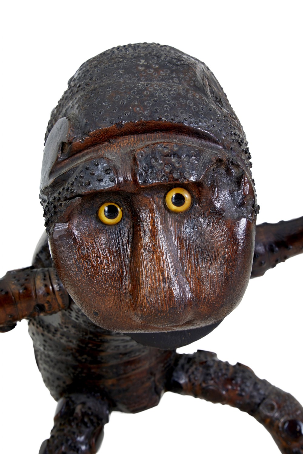 A dark brown hand-carved mango wood novelty figure with inset yellow glass eyes and long textured limbs. View VII