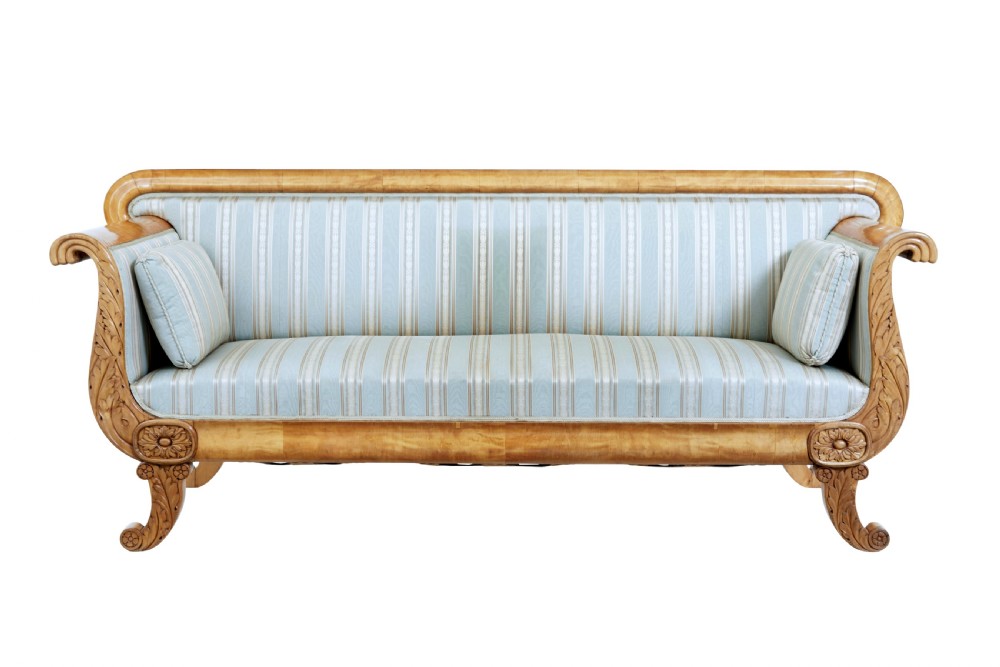 A 19th-century Swedish carved birch sofa featuring scrolled arms, floral rosettes, swept feet, and light blue and white striped upholstery. View II