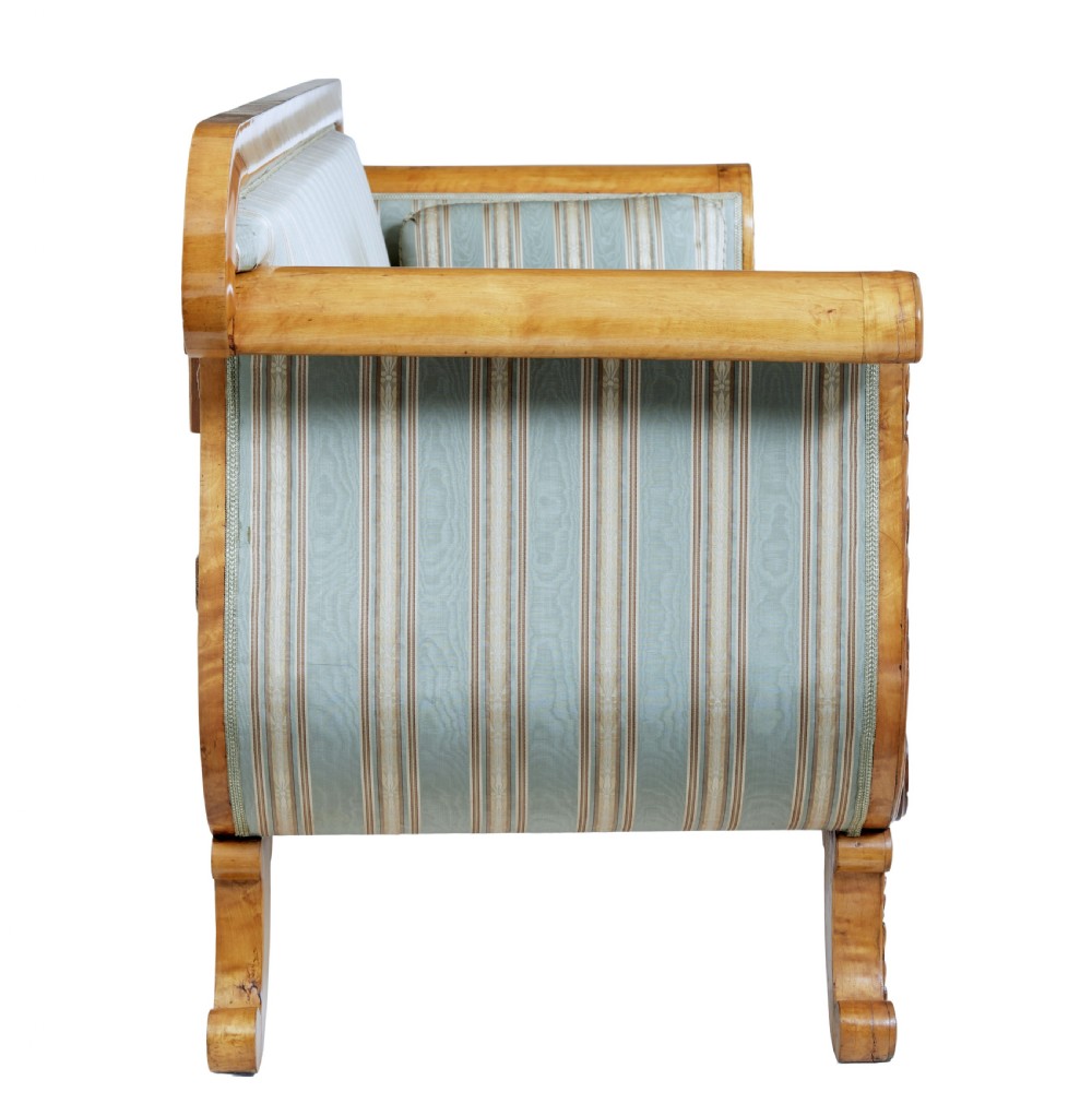 A 19th-century Swedish carved birch sofa featuring scrolled arms, floral rosettes, swept feet, and light blue and white striped upholstery. View III