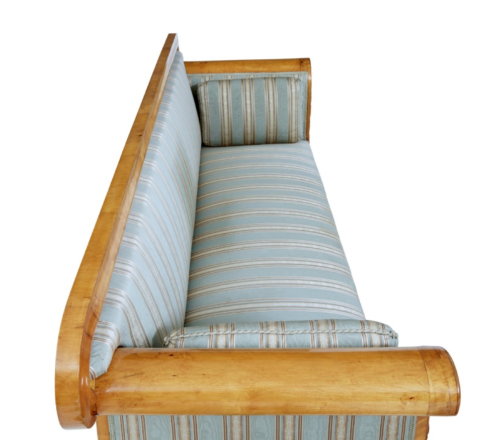 A 19th-century Swedish carved birch sofa featuring scrolled arms, floral rosettes, swept feet, and light blue and white striped upholstery. View VIII
