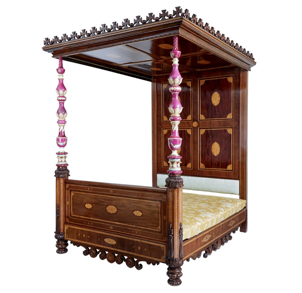 A nineteenth-century mahogany four-poster bed frame featuring carved posts with pink porcelain sections, marquetry panelling, and an ornate trefoil canopy trim. View IV