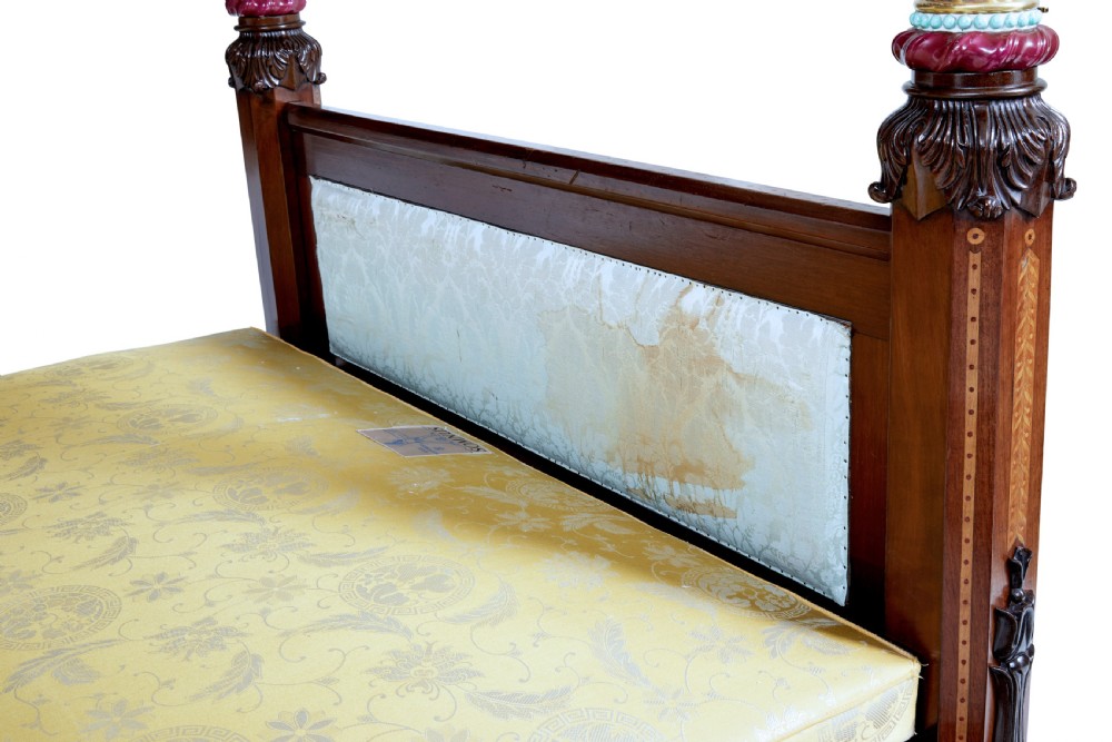 A nineteenth-century mahogany four-poster bed frame featuring carved posts with pink porcelain sections, marquetry panelling, and an ornate trefoil canopy trim. View XX