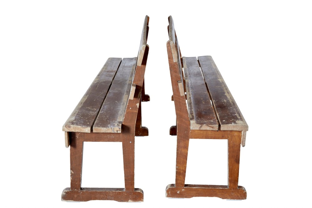 A pair of long, rustic pine benches with slatted backrests, trestle-style legs, and a distressed reddish-brown painted finish. View III