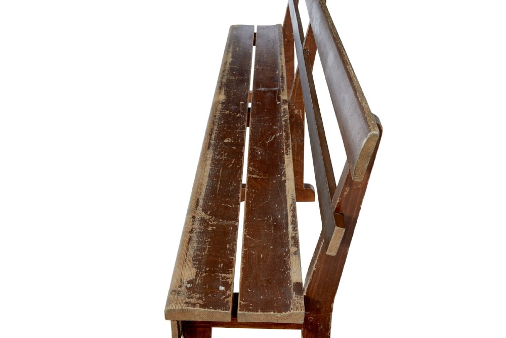 A pair of long, rustic pine benches with slatted backrests, trestle-style legs, and a distressed reddish-brown painted finish. View VII