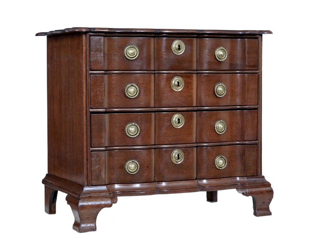 A 19th-century oak chest featuring four graduated drawers with shaped fronts, brass ring handles, keyhole escutcheons, and bracket feet.