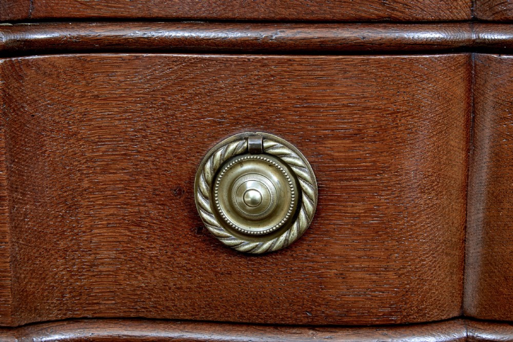 A 19th-century oak chest featuring four graduated drawers with shaped fronts, brass ring handles, keyhole escutcheons, and bracket feet. View VIII
