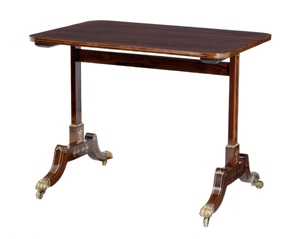 An early 19th-century Regency dark wood side table with delicate brass inlay, trestle base, and brass claw feet on castors.