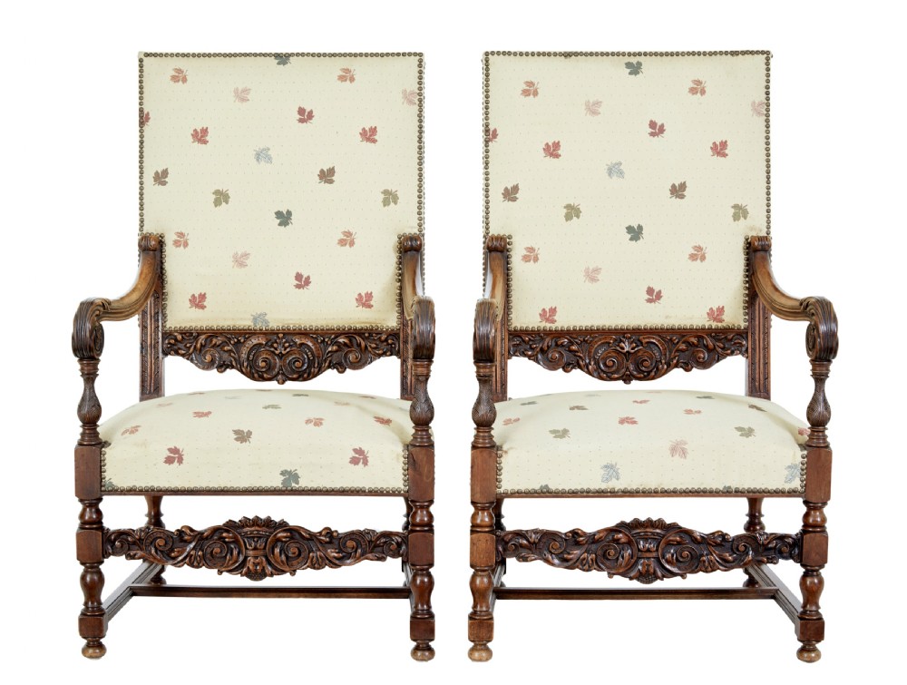 Pair of 19th-century French carved walnut armchairs with high rectangular backs, scroll arms, and cream leaf-patterned upholstery.