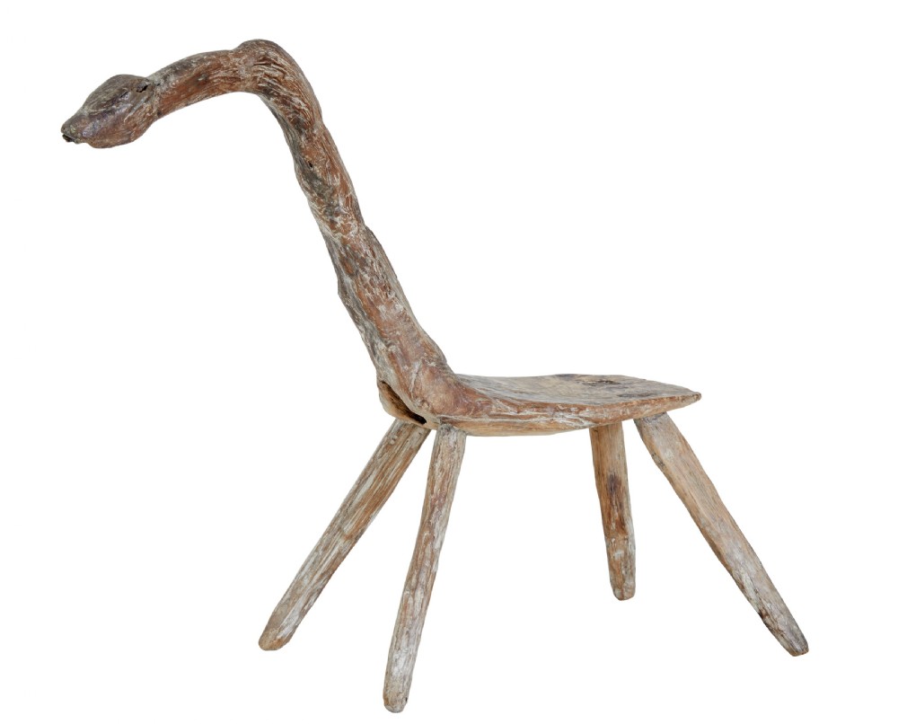 A rustic 19th-century childs stool crafted from weathered natural form oak timber, featuring a curved zoomorphic backrest and four splayed legs.