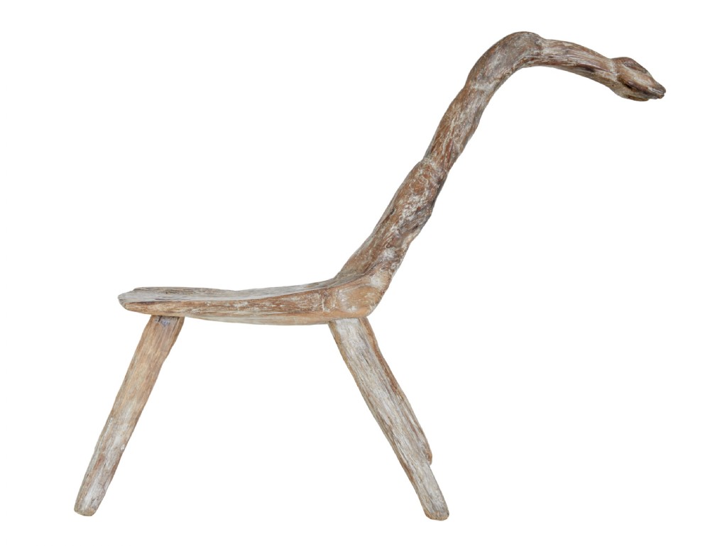 A rustic 19th-century childs stool crafted from weathered natural form oak timber, featuring a curved zoomorphic backrest and four splayed legs. View III
