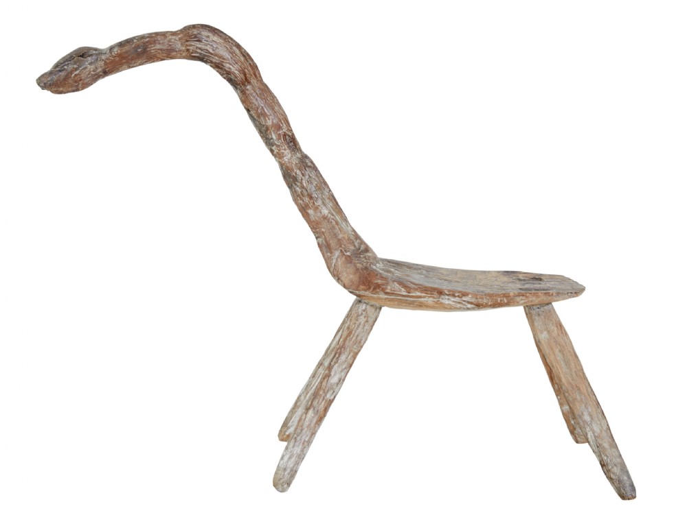 A rustic 19th-century childs stool crafted from weathered natural form oak timber, featuring a curved zoomorphic backrest and four splayed legs. View IV