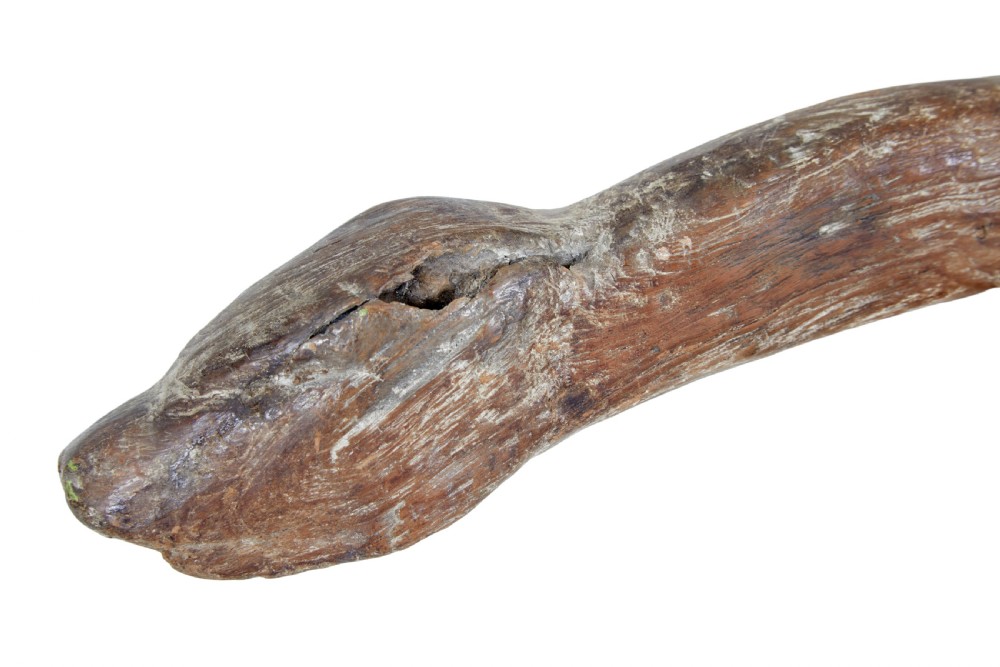 A rustic 19th-century childs stool crafted from weathered natural form oak timber, featuring a curved zoomorphic backrest and four splayed legs. View VII
