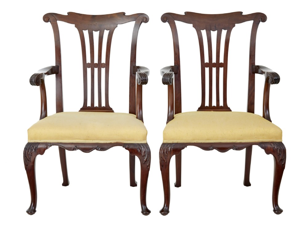 A pair of 19th-century Chippendale style mahogany armchairs featuring pierced back splats, curved armrests, yellow upholstered drop-in seats, and carved cabriole legs.