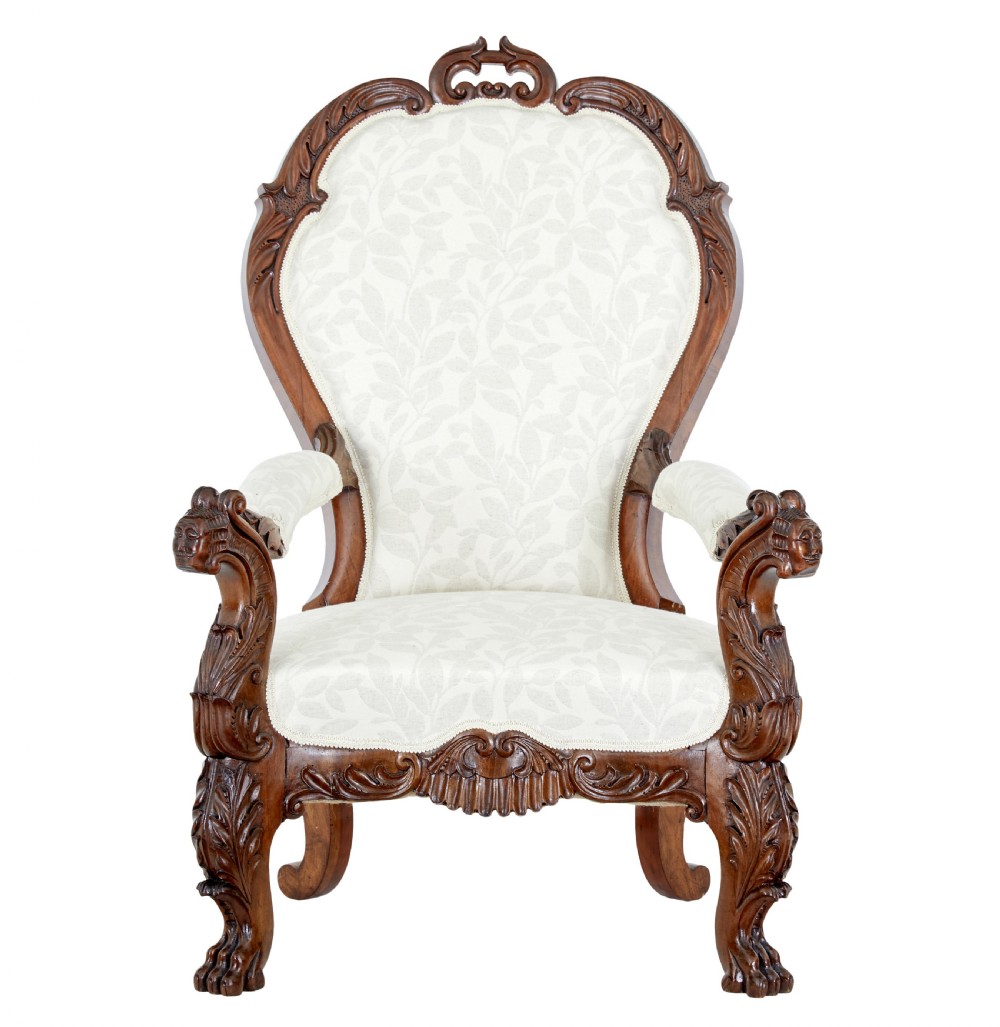 A mid-19th-century carved walnut armchair featuring figurative arm supports and cream patterned upholstery. View II