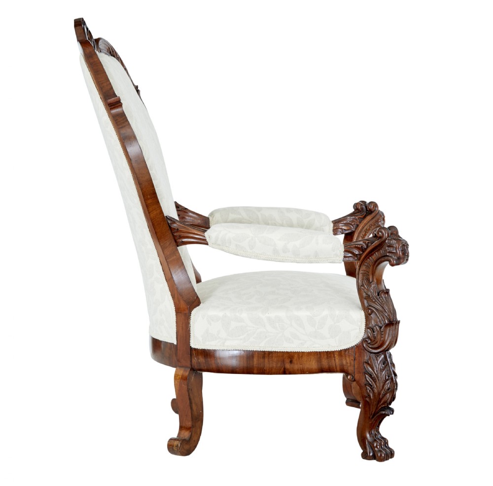 A mid-19th-century carved walnut armchair featuring figurative arm supports and cream patterned upholstery. View IV