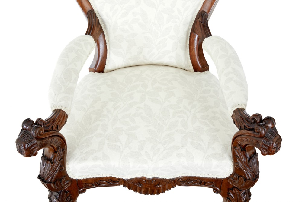 A mid-19th-century carved walnut armchair featuring figurative arm supports and cream patterned upholstery. View VI