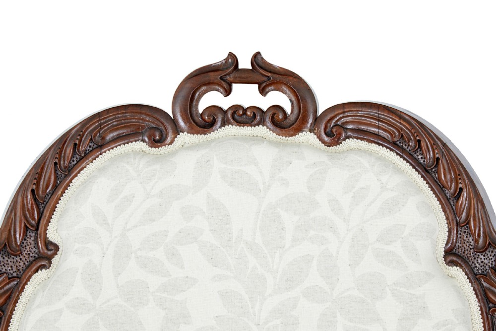 A mid-19th-century carved walnut armchair featuring figurative arm supports and cream patterned upholstery. View VII