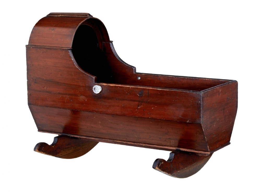 A Victorian pine rocking cradle featuring a curved canopy hood, a dark reddish-brown finish, and two solid wood rockers at the base.