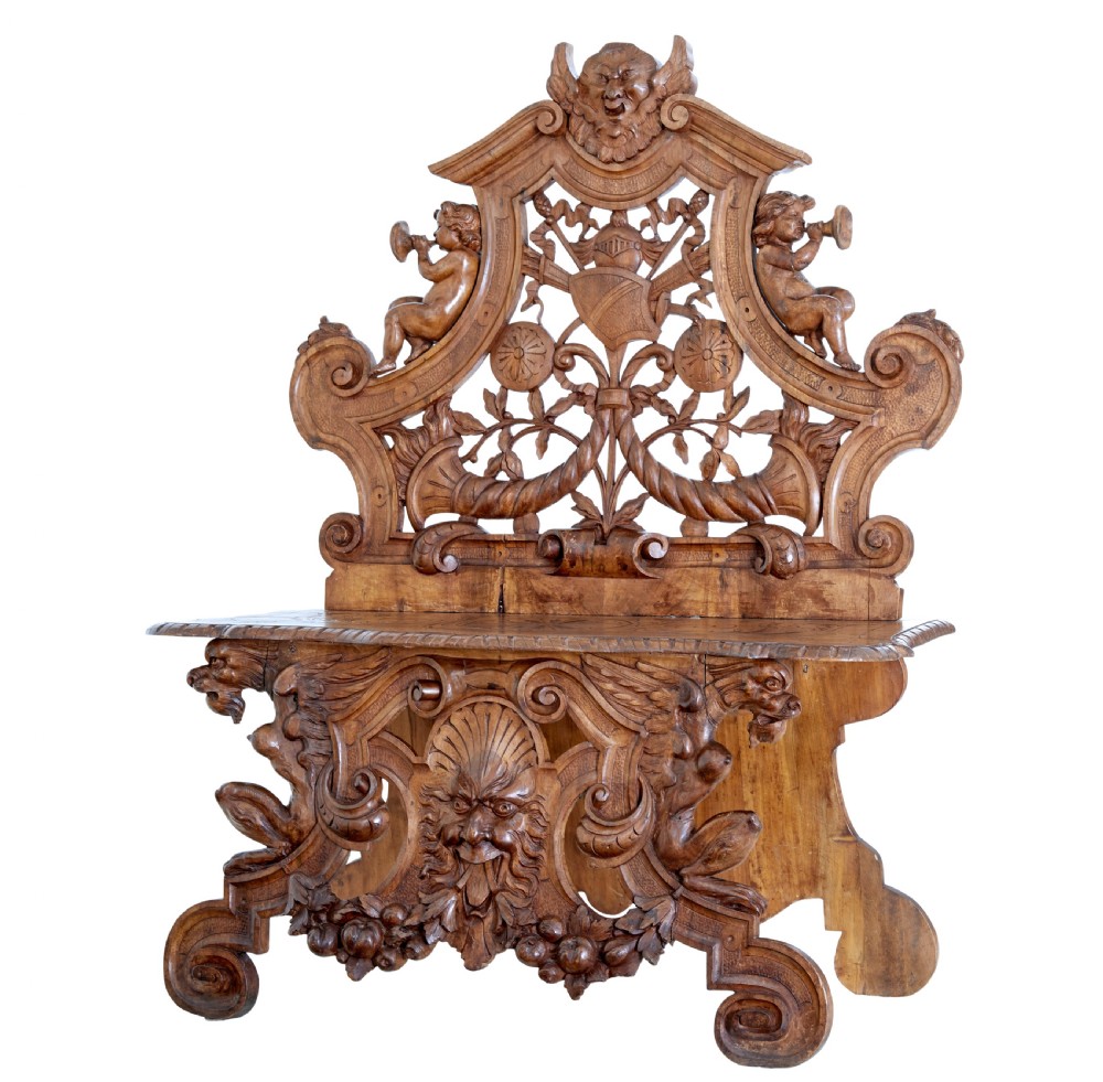 A 19th-century Flemish walnut hall chair decorated with openwork carvings of grotesque masks, cherubs blowing trumpets, and a central shield motif.