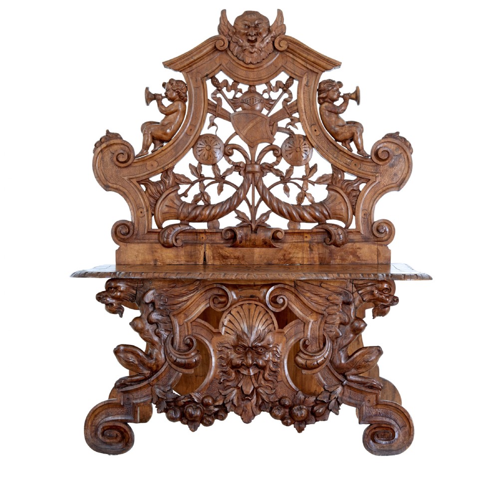 A 19th-century Flemish walnut hall chair decorated with openwork carvings of grotesque masks, cherubs blowing trumpets, and a central shield motif. View II