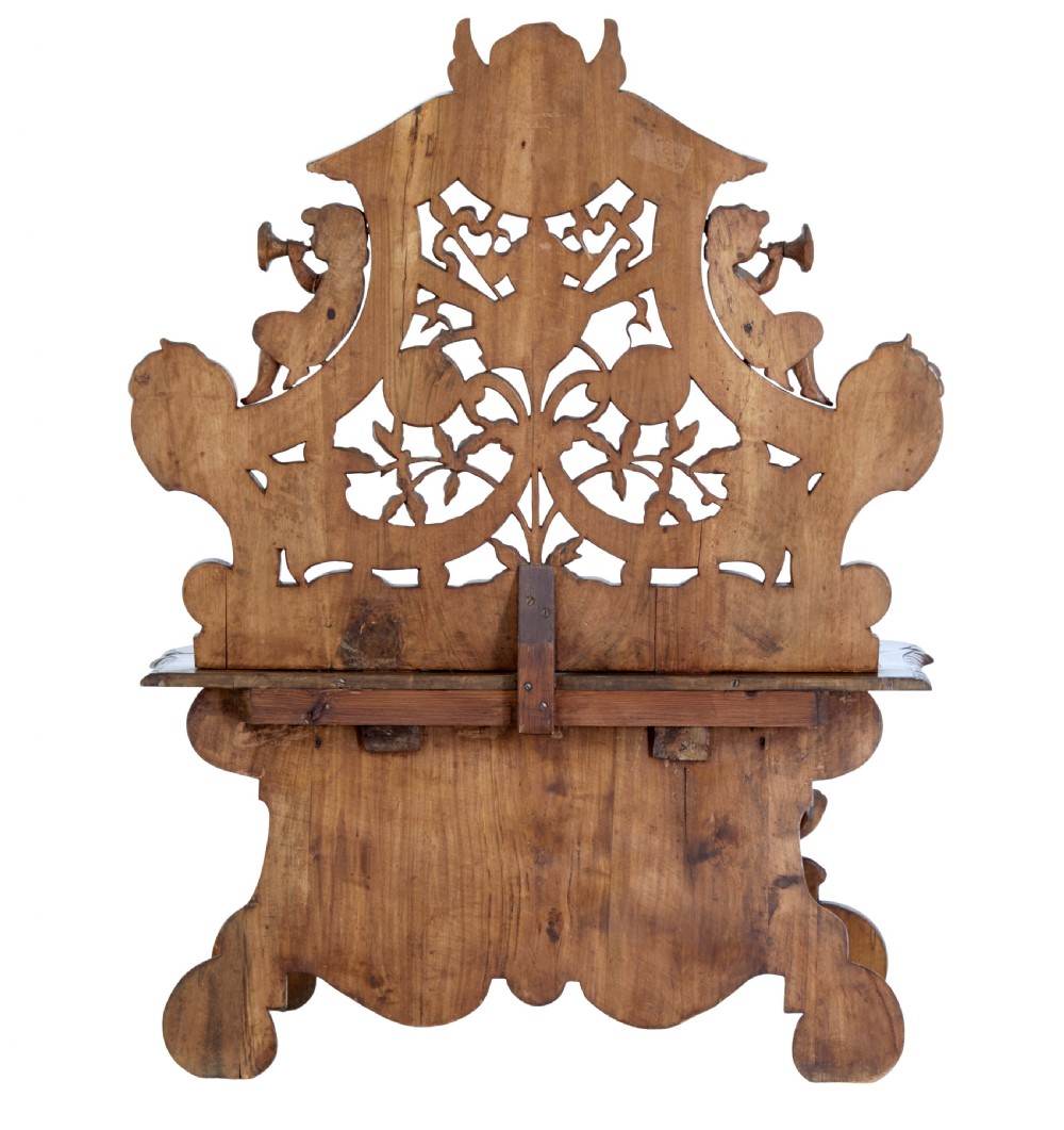 A 19th-century Flemish walnut hall chair decorated with openwork carvings of grotesque masks, cherubs blowing trumpets, and a central shield motif. View IV