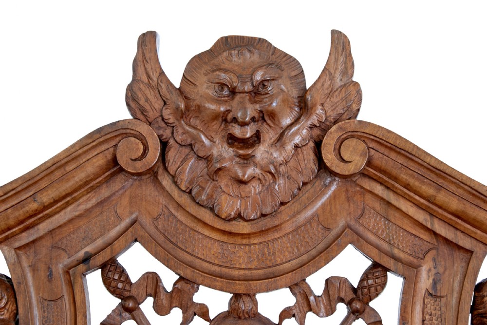 A 19th-century Flemish walnut hall chair decorated with openwork carvings of grotesque masks, cherubs blowing trumpets, and a central shield motif. View VI